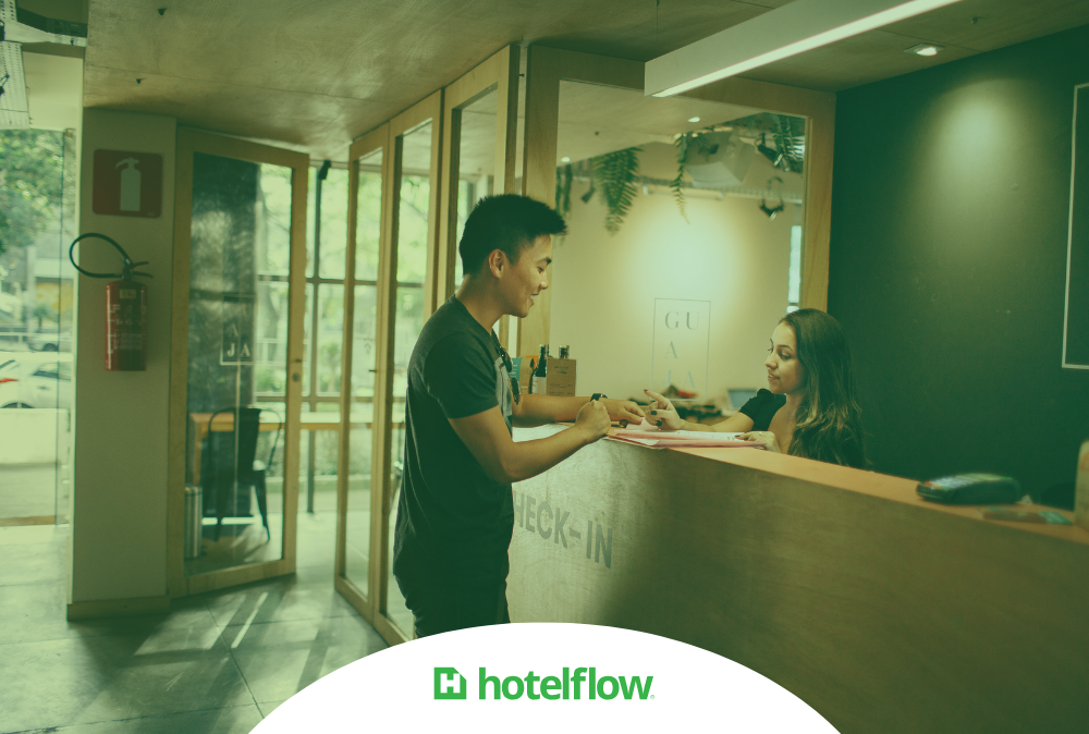 Hóspede atendido por recepcionista no balcão de um hotel, ilustrando a produtividade na hotelaria.